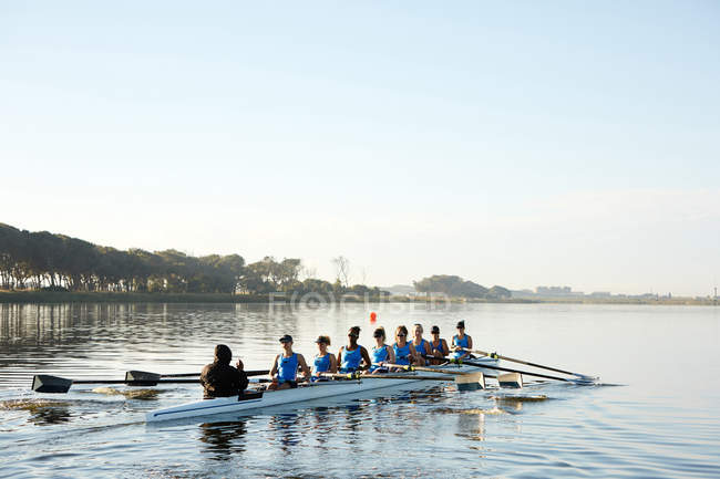 Female rowers rowing scull on lake below blue sky — Stock Photo