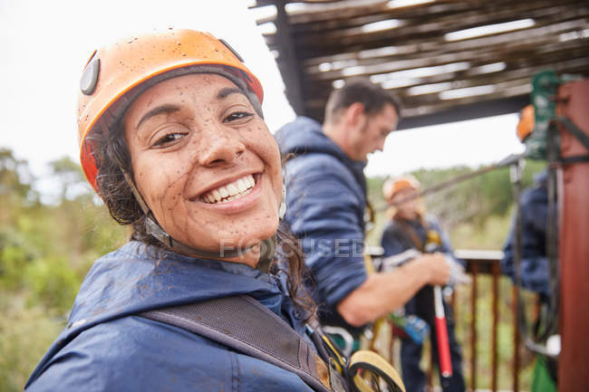 Portrait enthusiastic, muddy young woman enjoying zip lining — Stock Photo