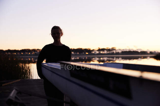 Silhouette del rematore femmina che solleva il cranio sul molo del lago all'alba — Foto stock