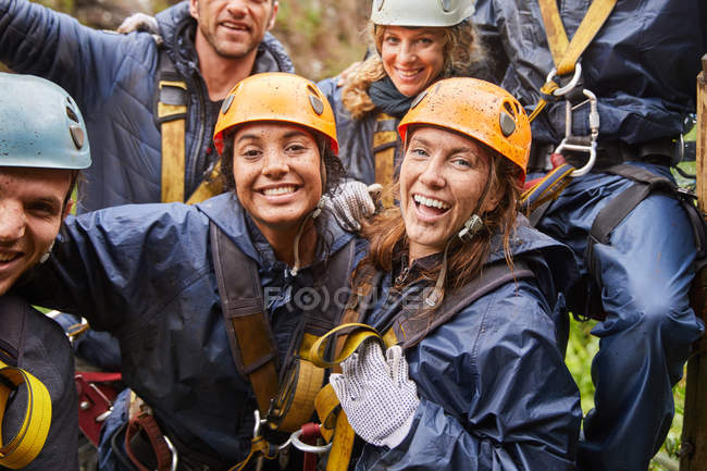 Portrait happy, muddy friends zip lining — Stock Photo