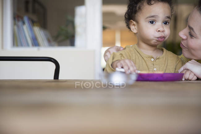 Glücklich kaukasische Mutter füttert kleinen afrikanisch-amerikanischen Sohn — Stockfoto