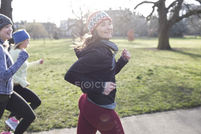 Corredor femenino seguro corriendo en el soleado parque - foto de stock
