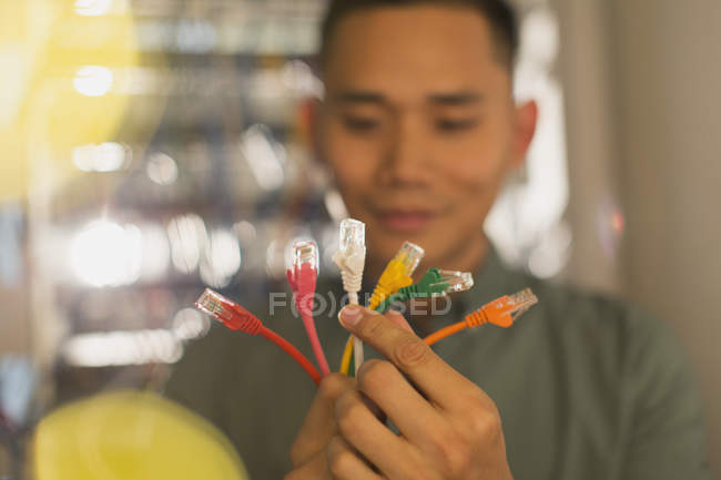 Männlicher IT-Techniker untersucht mehrfarbige Verbindungsstecker — Stockfoto