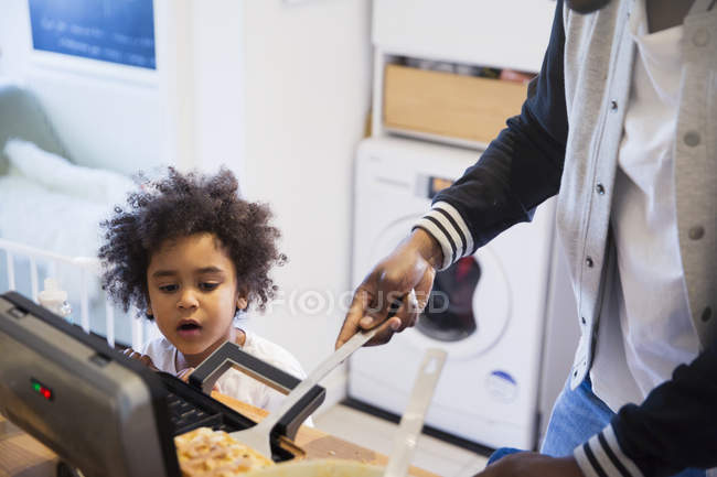 Cropped image of father and curious daughter baking waffles — Stock Photo