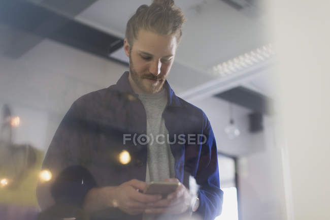 Uomo d'affari sms con smart phone in ufficio — Foto stock