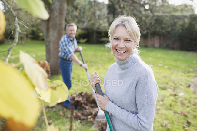 Maduro casal caucasiano com ancinhos trabalhando no jardim — Fotografia de Stock