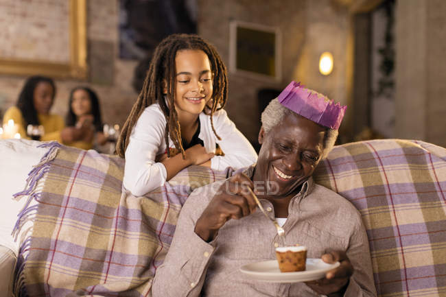 Nipote guardando nonno in carta di Natale corona mangiare dessert — Foto stock