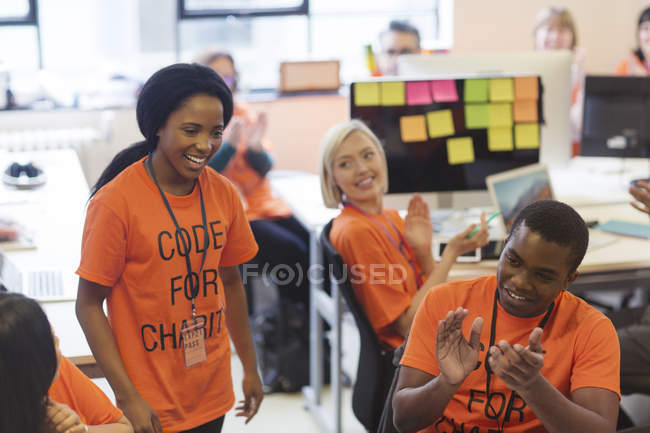 Hackers clapping for woman, coding for charity at hackathon — Stock Photo