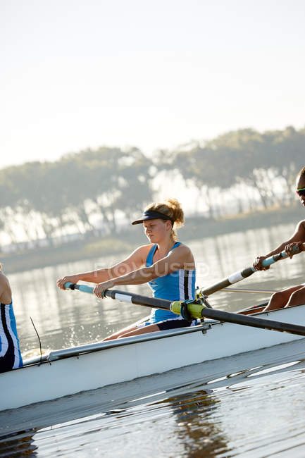 Determined female rower rowing scull on lake — Stock Photo