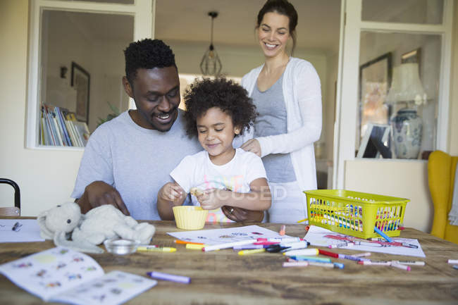 Los padres y la hija para colorear en la mesa juntos - foto de stock