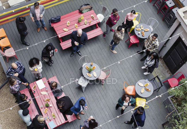 Overhead view friends socializing, drinking and eating at party on patio — Stock Photo
