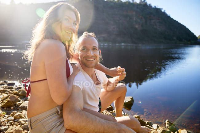 Нежная, беззаботная пара, держащаяся за руки на солнечном озере — стоковое фото