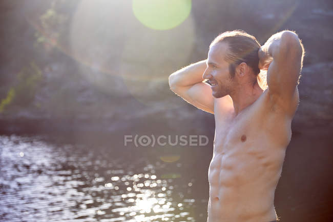 Despreocupado hombre de pecho desnudo en el soleado lago de verano - foto de stock