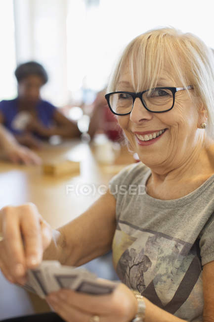 Retrato feliz mujer mayor jugando a las cartas en el centro comunitario - foto de stock