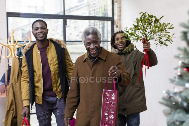 Happy grandfather and grandsons arriving with Christmas gift and mistletoe — Stock Photo