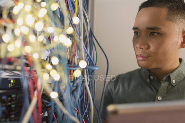 Tecnico IT maschio focalizzato che esamina i fili sul pannello server — Foto stock