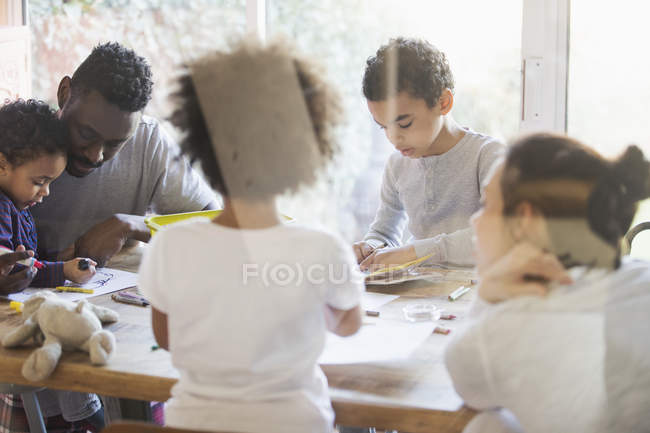 Família jovem em pijama para colorir na mesa de jantar — Fotografia de Stock