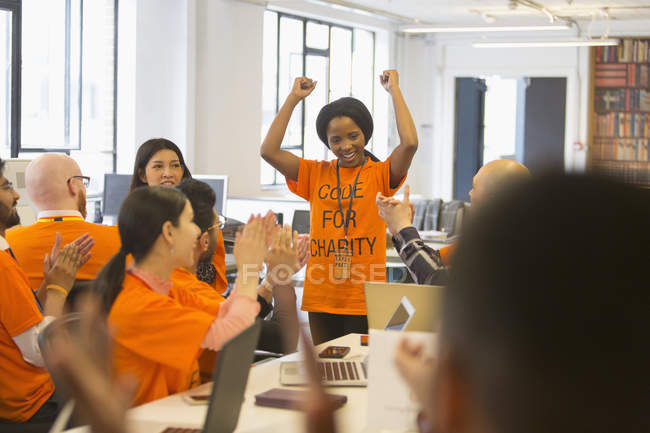 Happy hackers cheering for woman, coding for charity at hackathon — Stock Photo