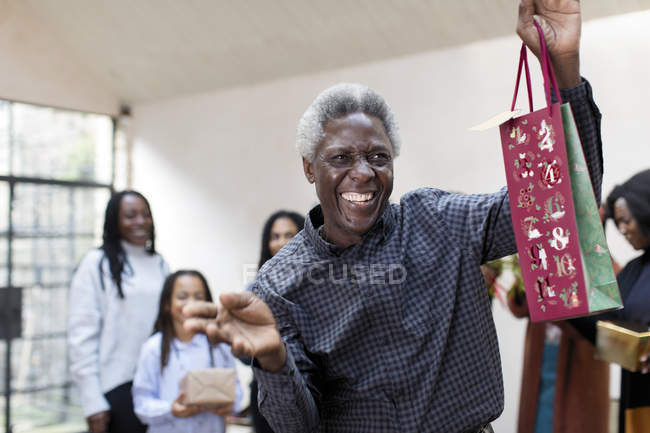 Portrait playful grandfather with Christmas gift — Stock Photo
