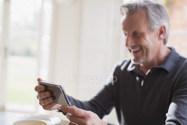 Улыбающийся взрослый мужчина с помощью смартфона — стоковое фото