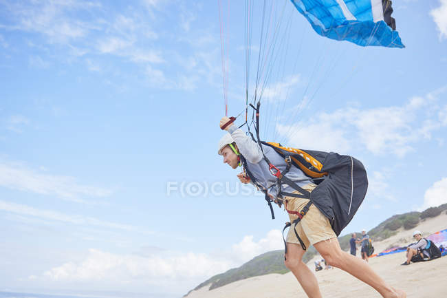Parapendio maschile corsa con paracadute sulla spiaggia — Foto stock