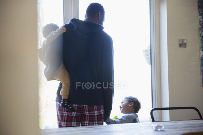Vista trasera del padre afroamericano con niños en casa - foto de stock