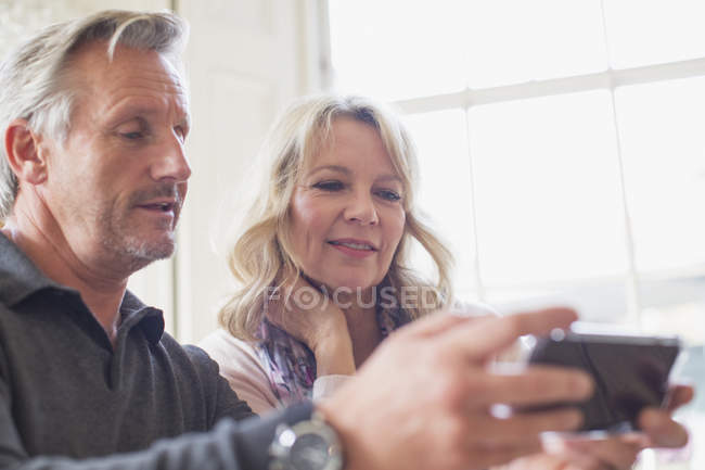 Casal maduro usando telefone inteligente em casa moderna — Fotografia de Stock
