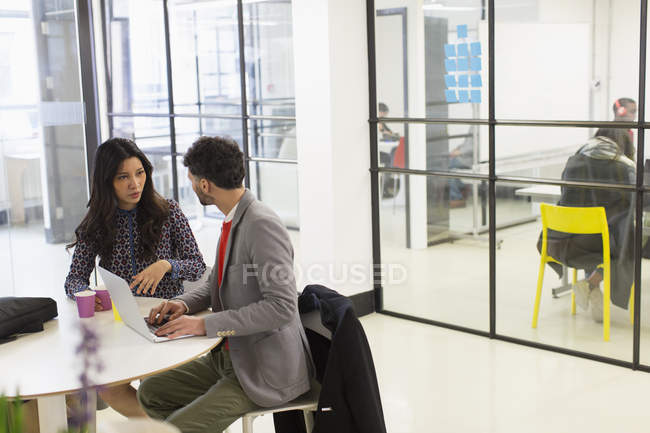 Les gens d'affaires parlent, en utilisant un ordinateur portable dans une réunion de bureau — Photo de stock
