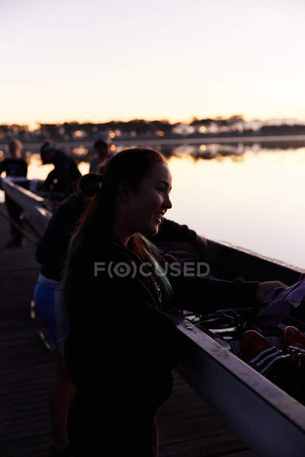 Sorrindo remador fêmea em scull no lago nascer do sol — Fotografia de Stock