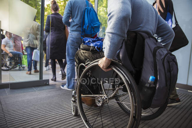 Обрезанное изображение человека в инвалидной коляске покидающего офис — стоковое фото