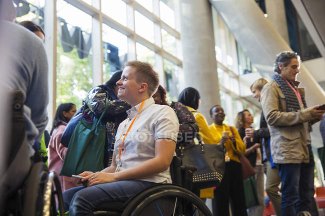 Усміхнена жінка в інвалідному візку на конференції в сучасному офісі — стокове фото