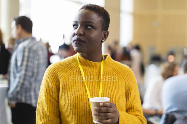 Thoughtful businesswoman drinking coffee at conference — Stock Photo