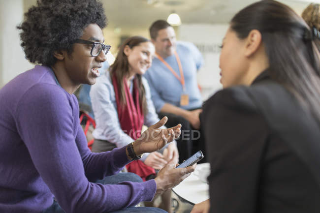 Business people with smart phone talking at conference — Stock Photo