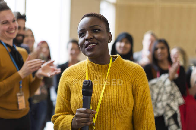 Altavoz sonriente de mujer de negocios con micrófono en la conferencia - foto de stock