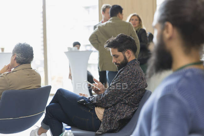 Businessman texting with smart phone in conference audience — Stock Photo