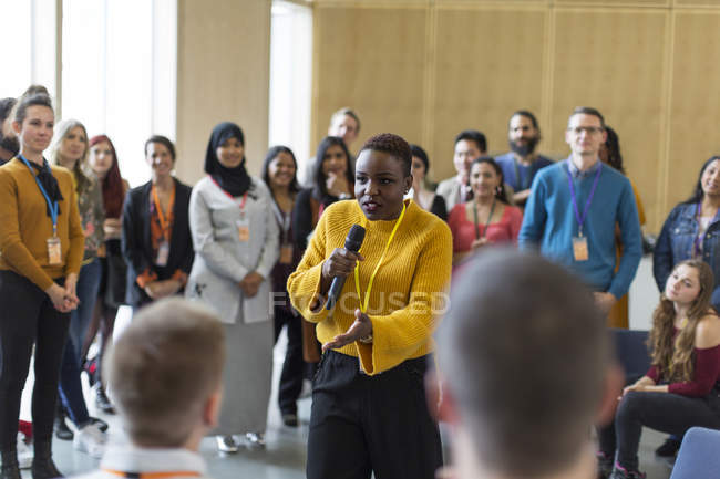 Audiência de conferência ouvindo alto-falante empresária com microfone — Fotografia de Stock