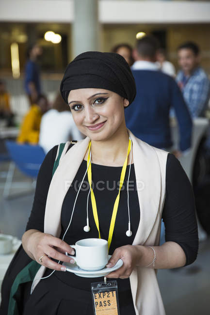 Портрет усміхнений, впевнена бізнес-леді в хедкарфі п'є каву на конференції — стокове фото