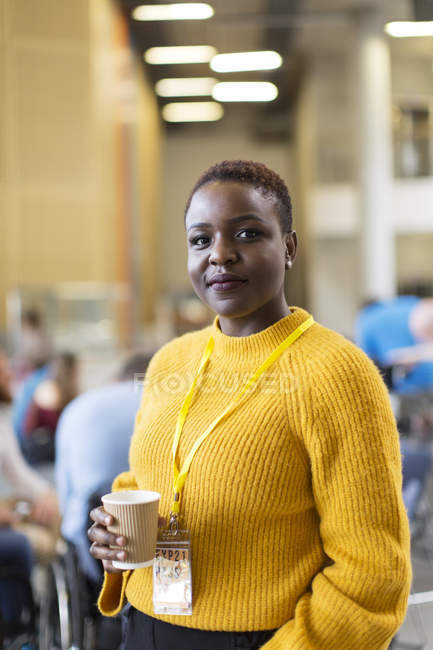 Portrait confident businesswoman drinking coffee at conference — Stock Photo