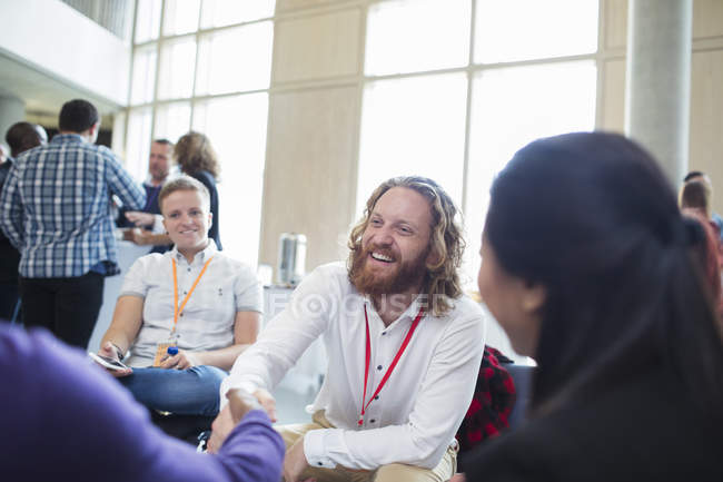 Усміхнений бізнесмен тремтить руками з колегою на конференції — стокове фото