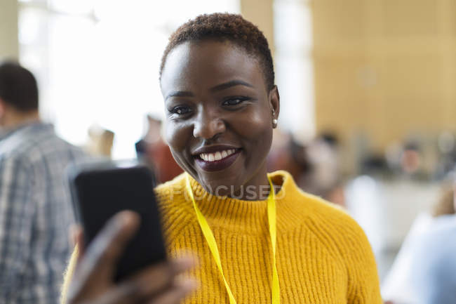 Smiling businesswoman using smart phone at modern office — Stock Photo