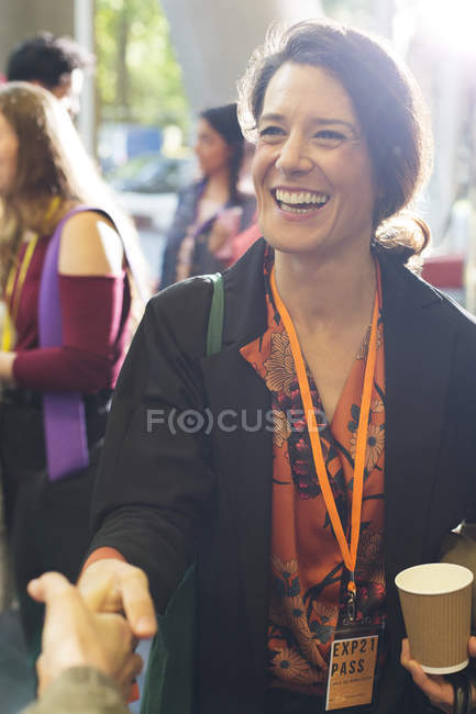 Усміхнена, захоплена бізнес-леді тремтить руками з колегою на конференції — стокове фото