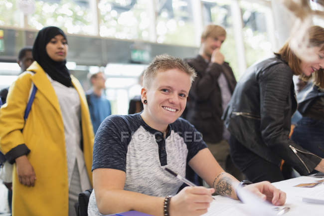 Portrait smiling woman in wheelchair checking in at conference registration table — Stock Photo