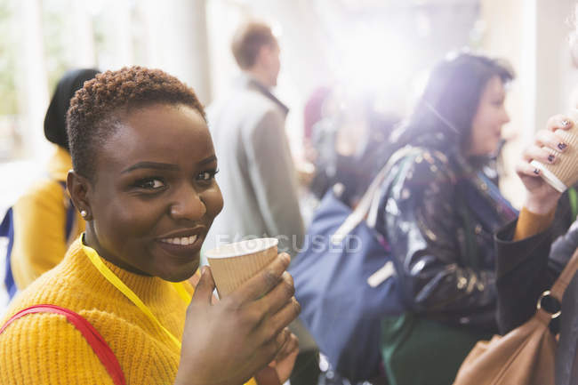 Portrait smiling businesswoman drinking coffee at conference — Stock Photo