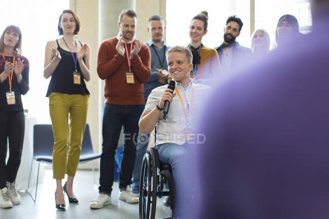 Audiencia aplaudiendo para oradora femenina en silla de ruedas - foto de stock