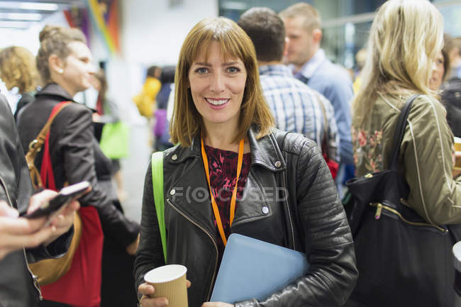 Retrato sonriente, empresaria confiada bebiendo café en la conferencia - foto de stock