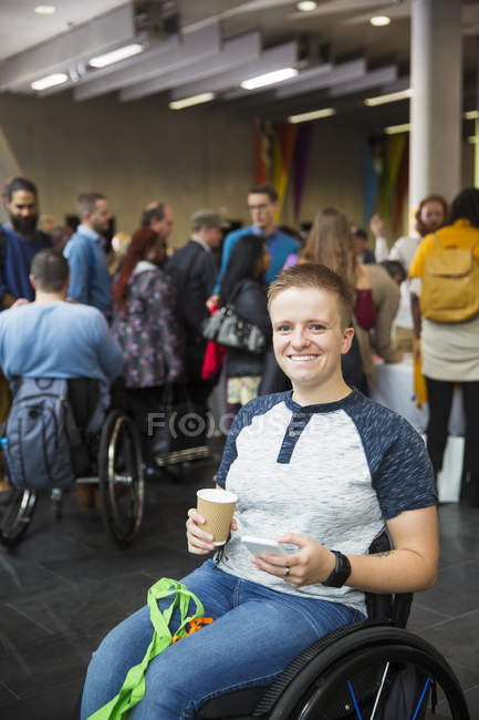 Porträt lächelt, selbstbewusste junge Frau im Rollstuhl trinkt Kaffee auf Konferenz — Stockfoto