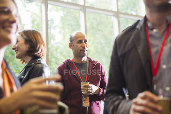 Geschäftsmann trinkt Kaffee, vernetzt sich auf Konferenz — Stockfoto