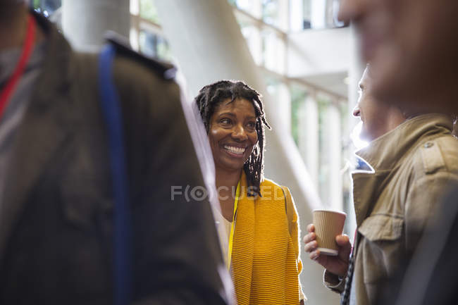 Sonriente mujer de negocios en red, hablando con su colega en la conferencia - foto de stock
