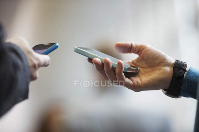 Close up men holding smart phones, blurred background — Stock Photo