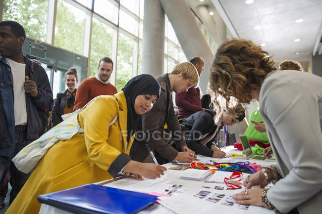 Empresaria en hijab llegando, registrándose en la mesa de inscripción de la conferencia - foto de stock